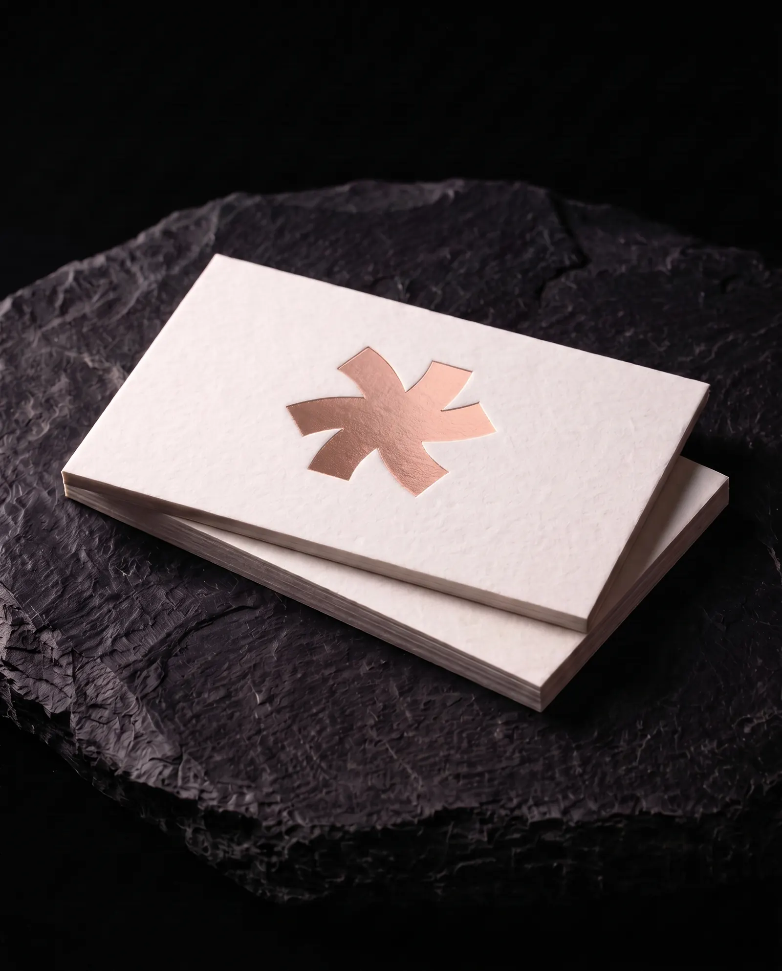 Rose gold hot foil business card on 32pt white cotton stock: the Print Peppermint mark stamped in rose gold foil, on a black slate plinth