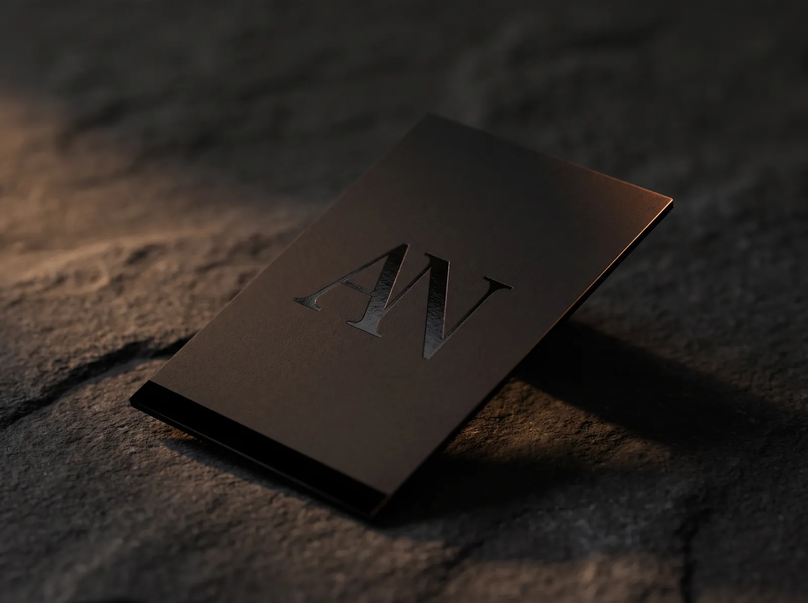 Black foil logo on black card at three angles, invisible flat and gleaming when tilted