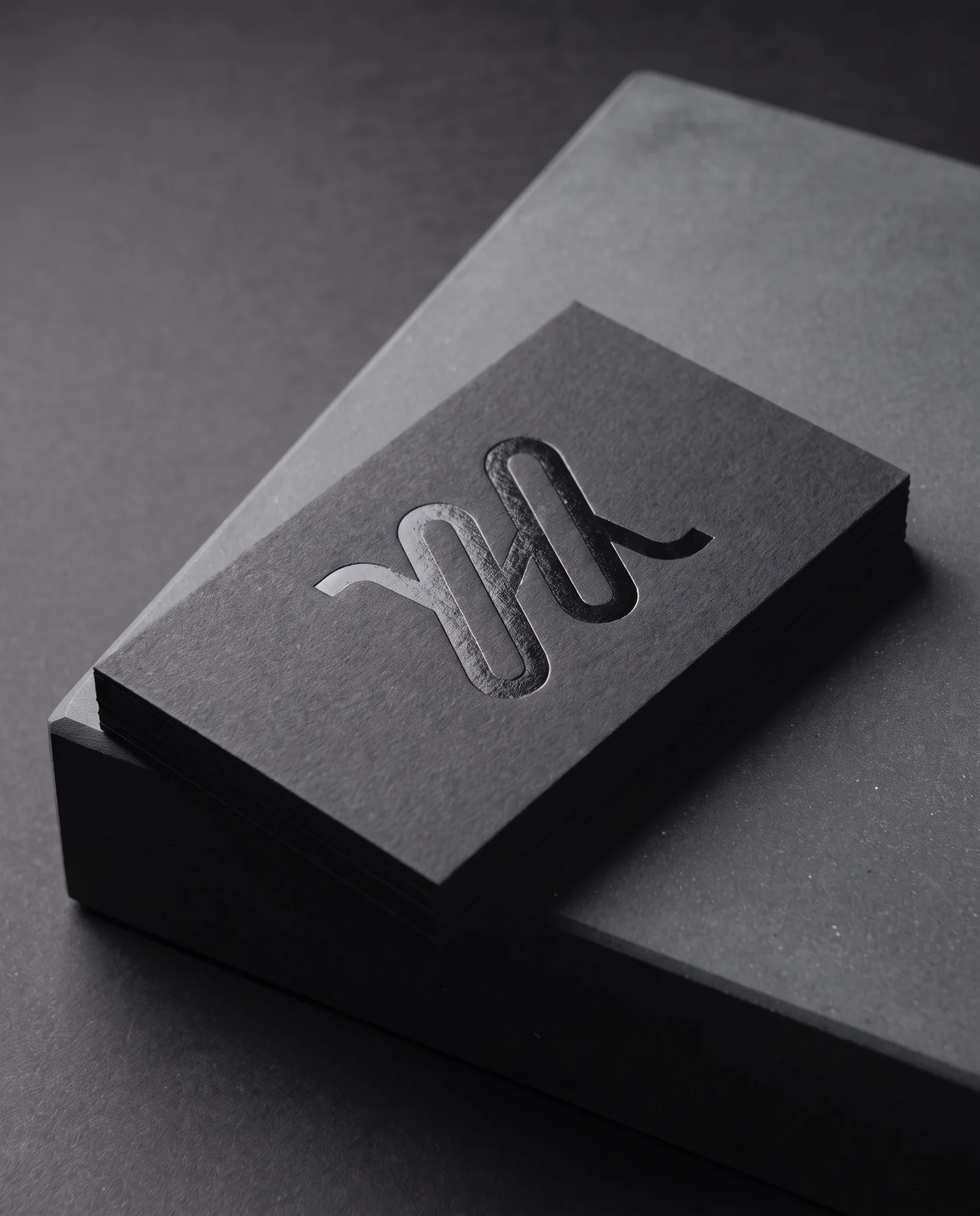 Semi-gloss black foil debossed into black cotton, tone on tone.