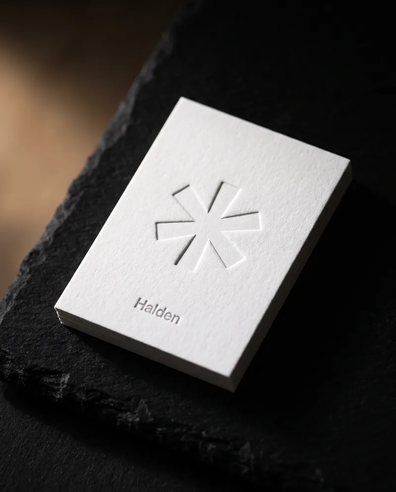 Thick white cotton business card with blind-debossed asterisk and small grey letterpress name