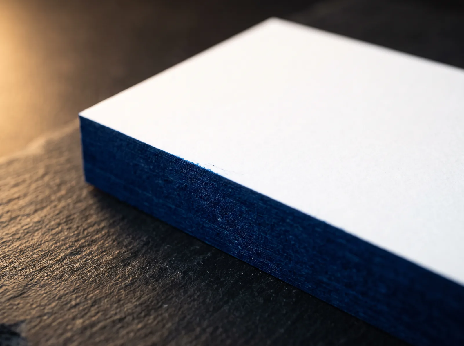 Close-up of a painted card edge: solid color absorbed into the cut paper, square corner