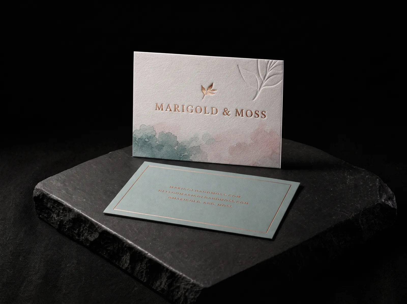 Copper-foiled, debossed cotton business cards for Marigold & Moss on a black slate plinth