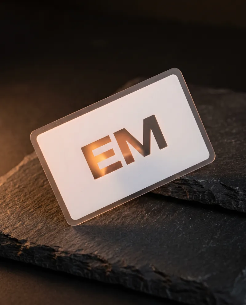 Frosted plastic business card with white flood and glowing translucent EM monogram window
