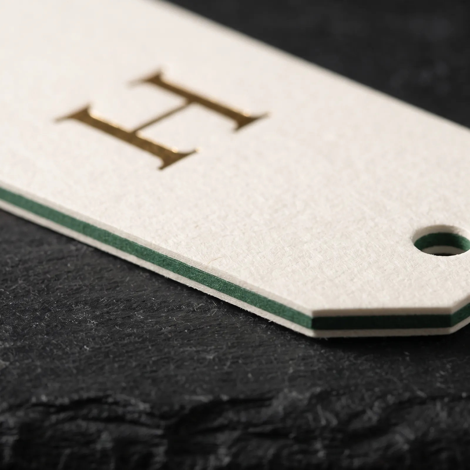 Edge of a duplex hang tag showing a green layer bonded between ivory cotton