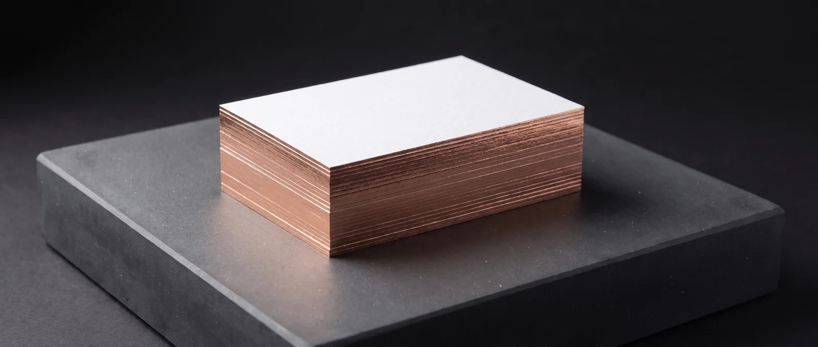 A stack of thick cotton cards with a mirror rose-gold foiled edge.
