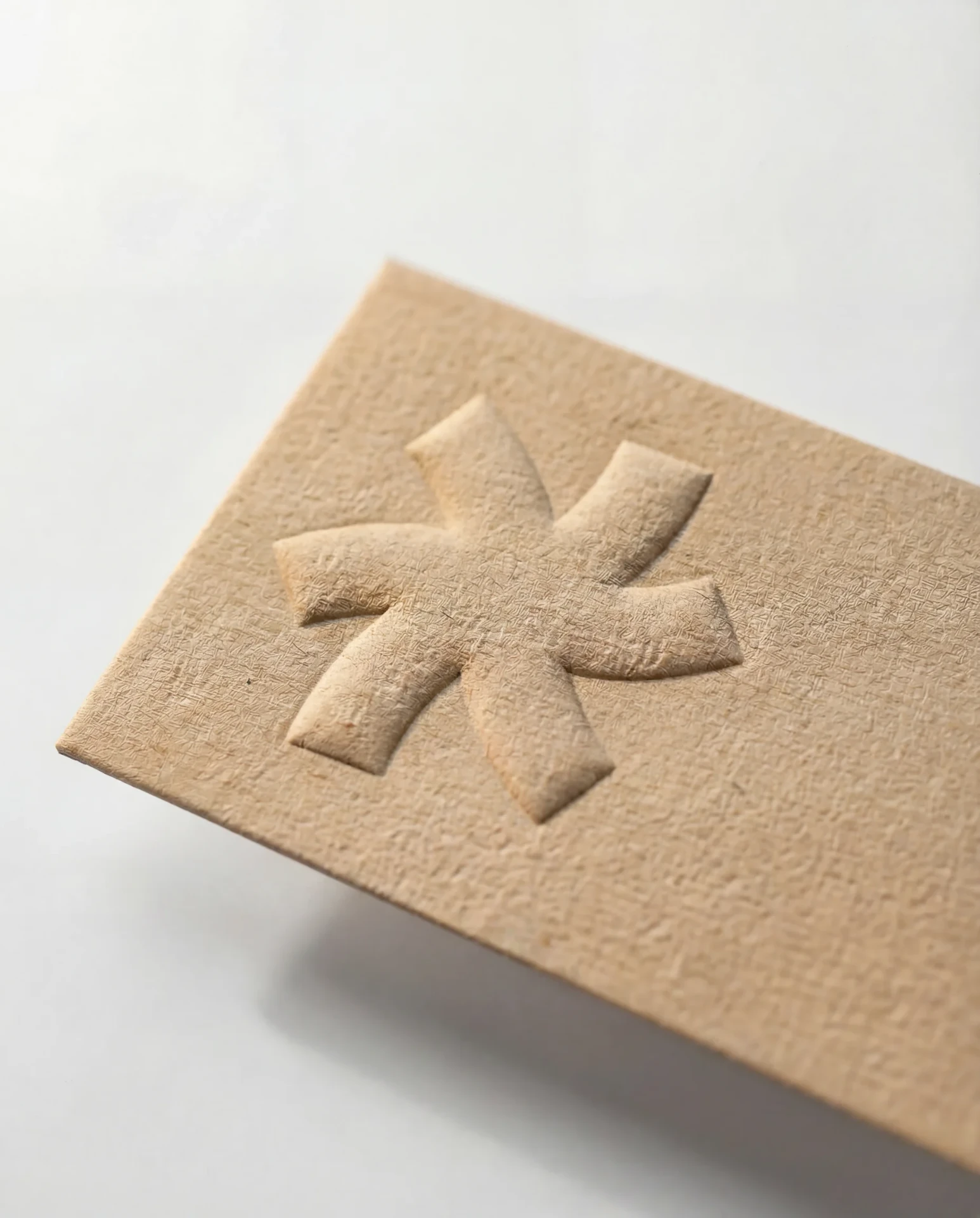 Blind emboss on kraft business card stock, the raised mark caught by side light