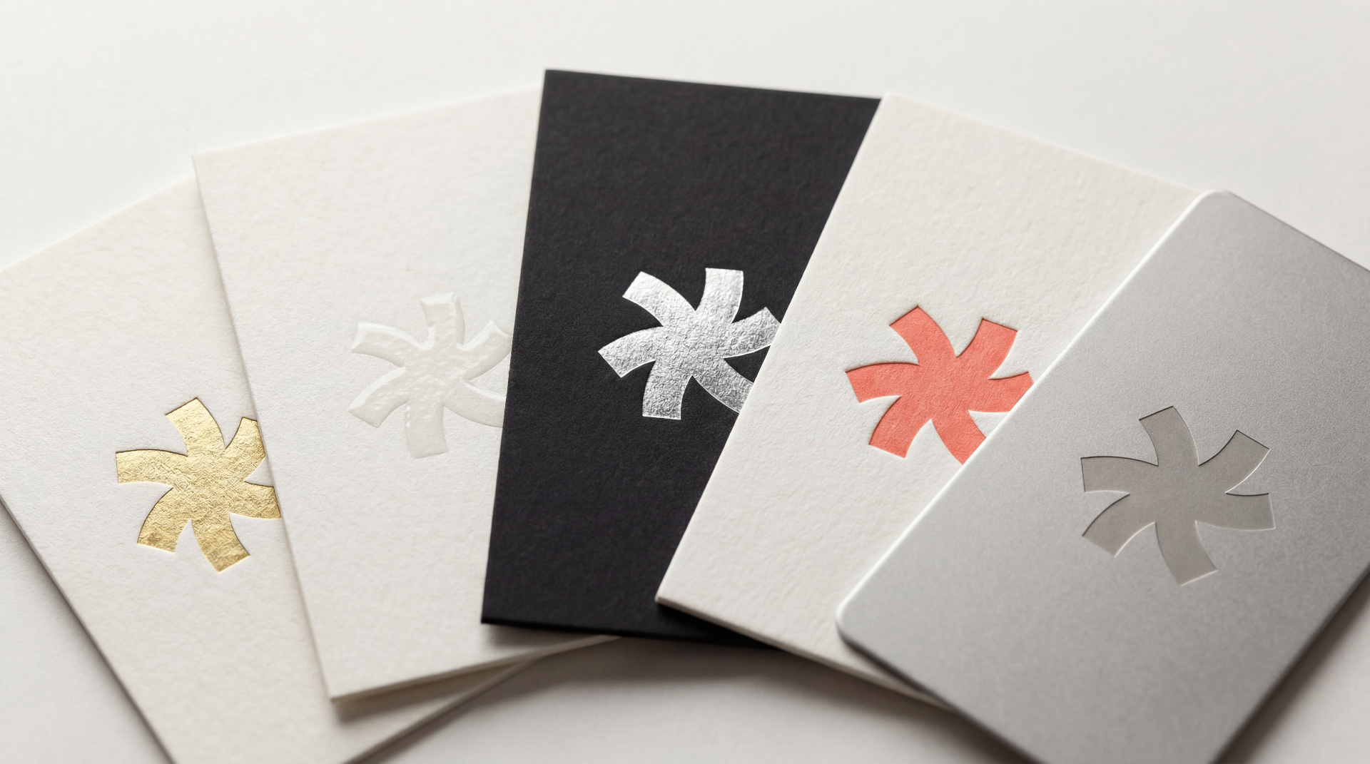 Fanned-out sample business cards showing gold foil, blind emboss, silver foil on black, coral letterpress, and metal finishes