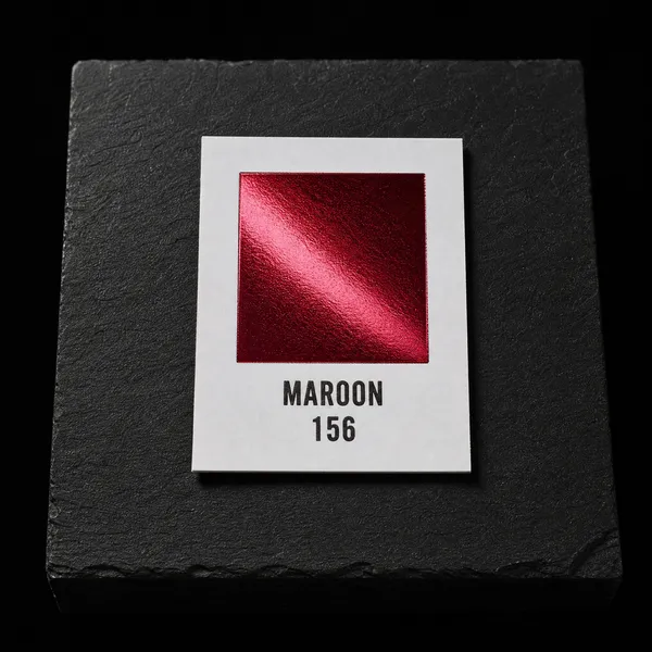 Maroon 156 foil chip photographed on slate